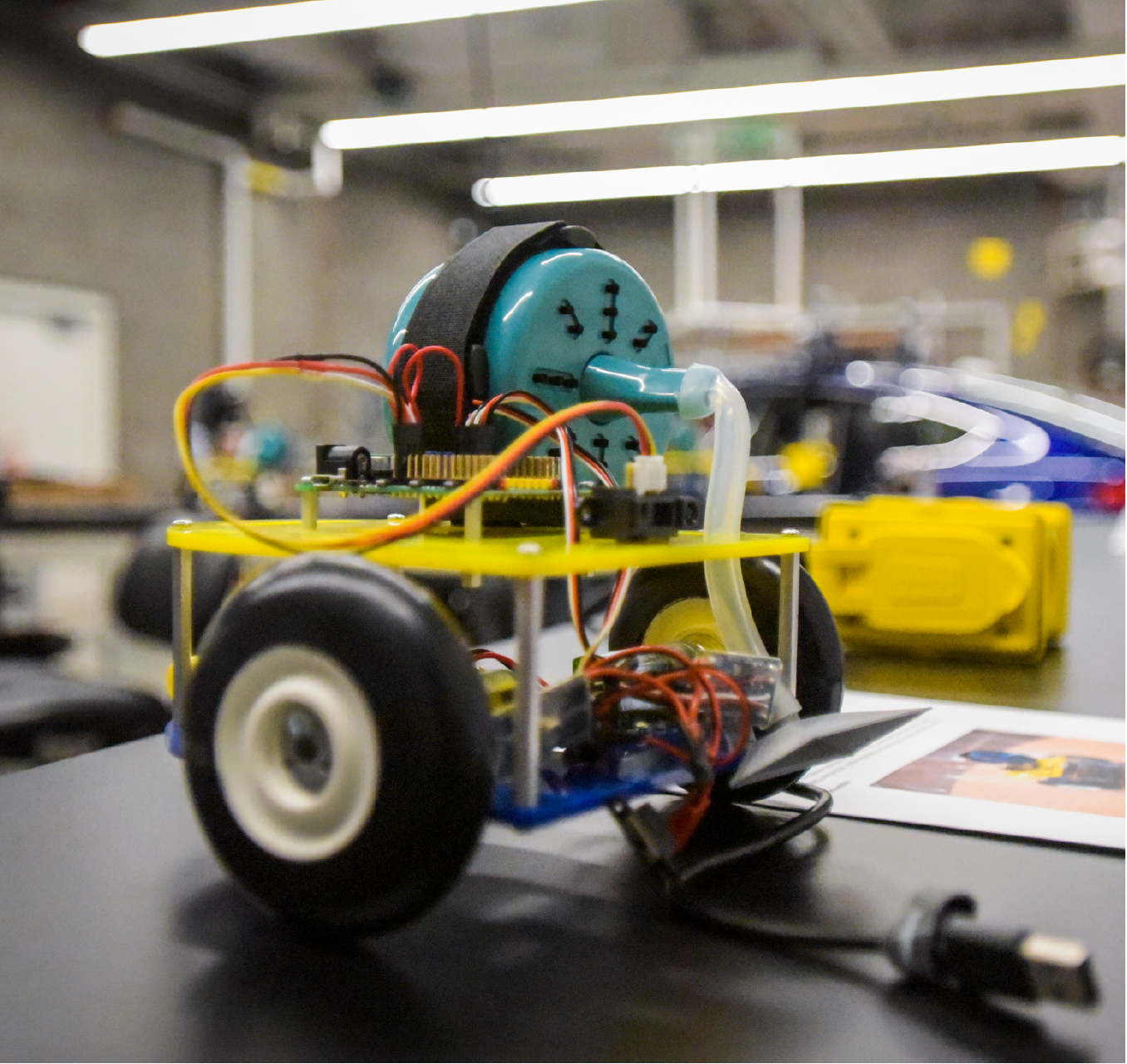 Small motorized project with two wheels and wires on top of lab bench