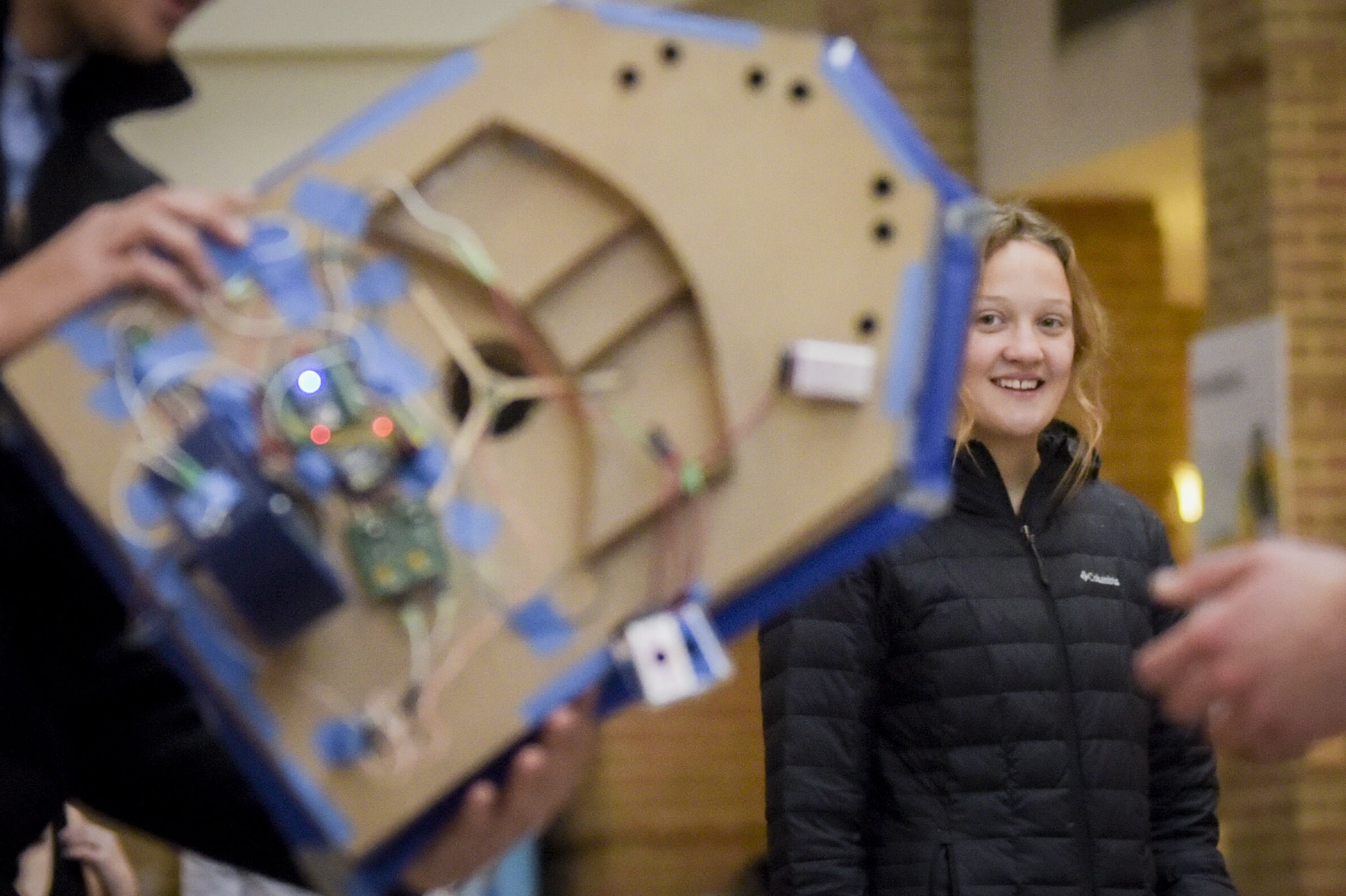 Student smiling at another student holding hovercraft vehicle in foreground