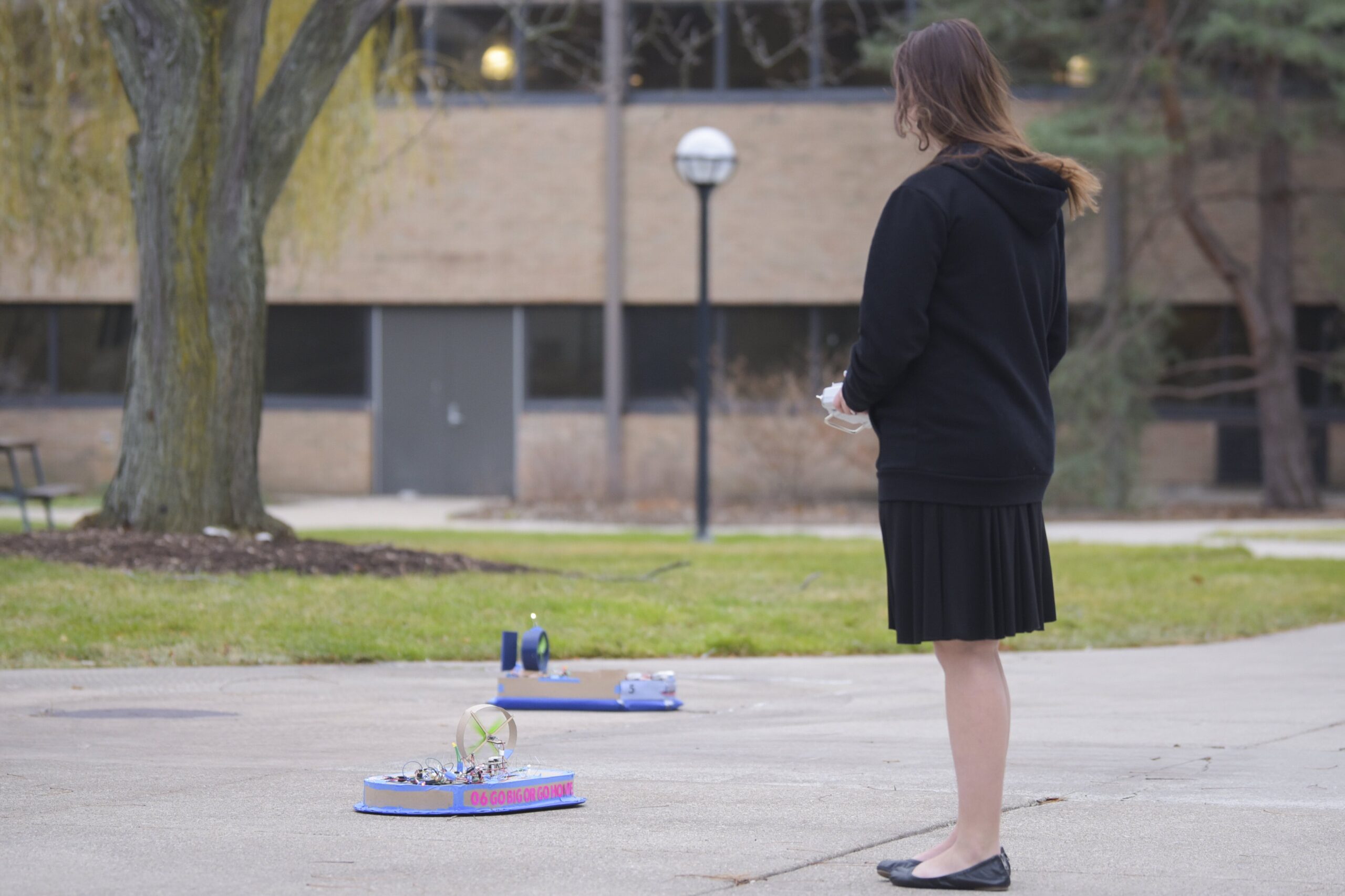 Back view of student looking at two hovercraft vehicles on ground outside