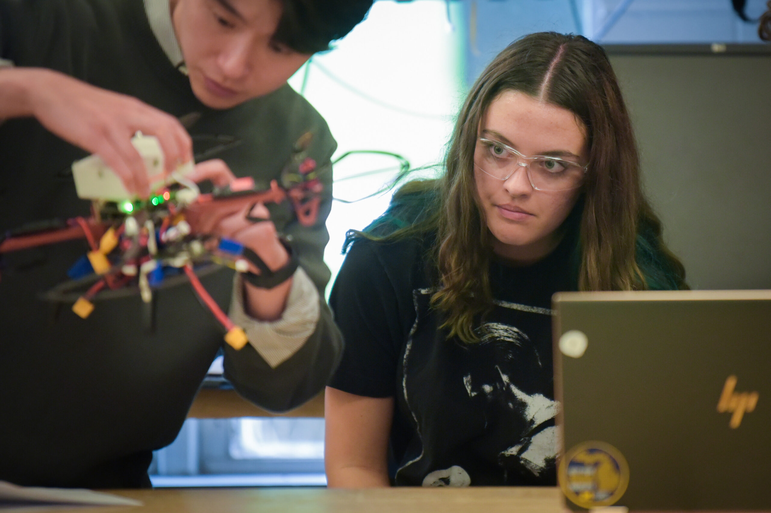 Student on right watching student on left adjust drone parts