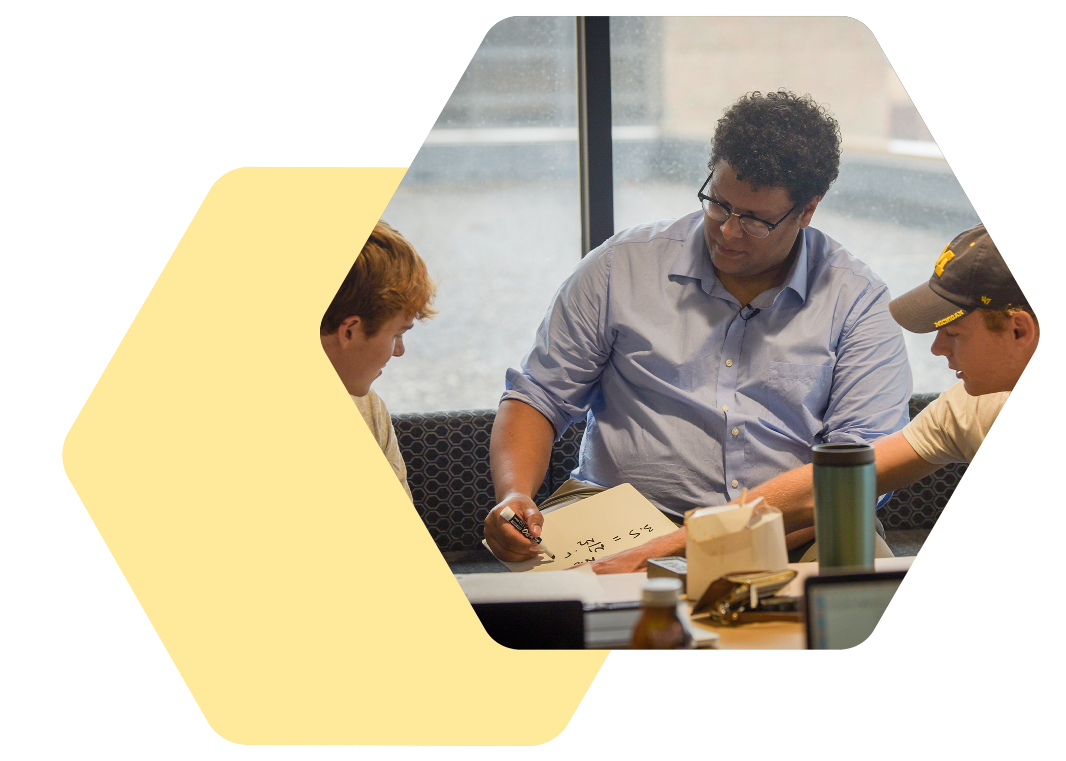 Instructor helping two students with a problem on whiteboard