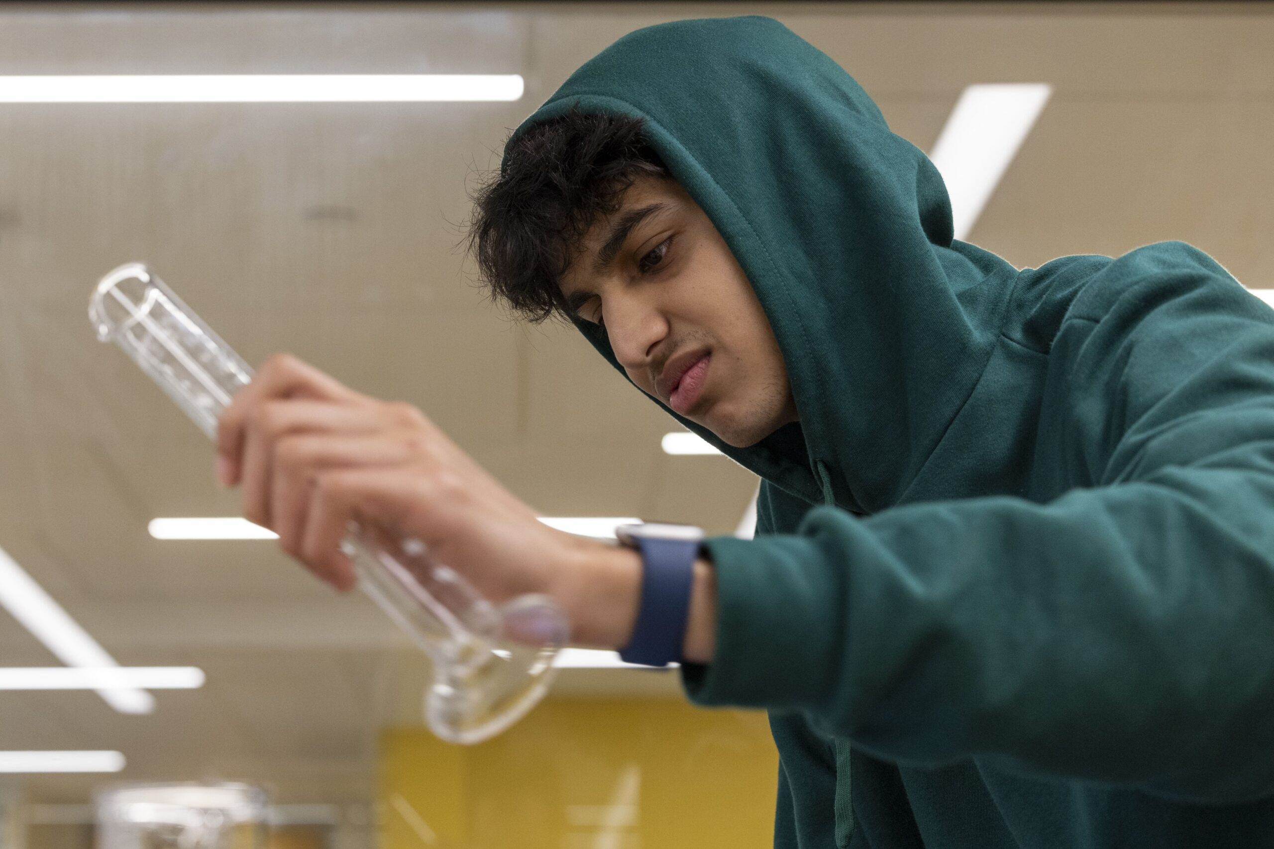 Students in lab attire side by side removing liquid from petri dish
