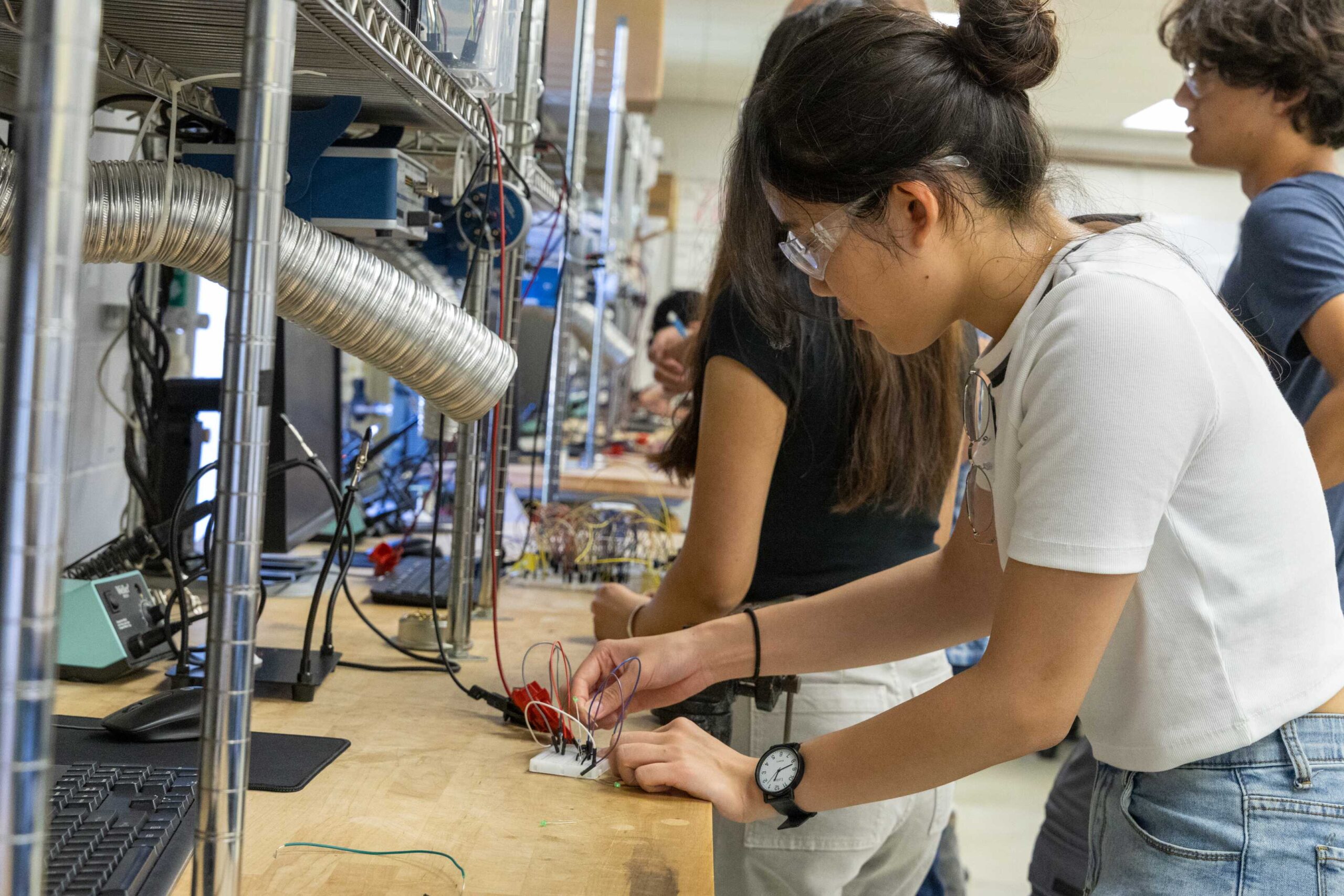 three students testing lab equipment