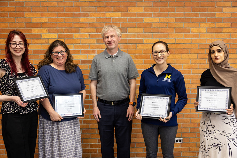 Kevin Pipe presenting "Teaching Award" to Lisa Grimble next to a headshot of Laura Hirshfield